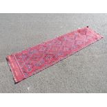 AN EASTERN WOOLLEN RUNNER RUG MAINLY RED GROUND 260 X 63 CM