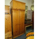 A HONEY PINE DOUBLE WARDROBE WITH AN ADDED TOP BOX