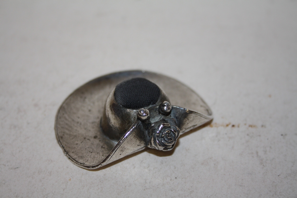 A WHITE METAL NOVELTY PIN CUSHION IN THE FORM OF A LADIES HAT