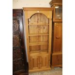 A HONEY PINE OPEN BOOKCASE WITH CUPBOARD H- W- CM