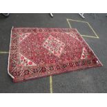 AN EASTERN WOOLLEN RUG MAINLY RED / CREAM GROUND 213 X 155 CM