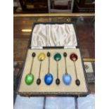 A CASED SET OF SIX ART DECO SILVER GILT AND ENAMEL COFFEE SPOONS, with turned wood bean terminals,