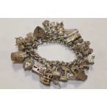 A HALLMARKED SILVER CHARM BRACELET WITH A LARGE QUANTITY OF CHARMS APPROX WEIGHT 136.5G