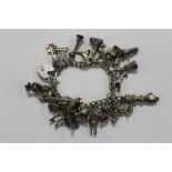 A SILVER CHARM BRACELET WITH A LARGE QUANTITY OF CHARMS APPROX WEIGHT 63.4G