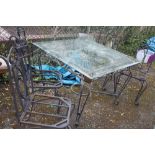 A HEAVY METAL GARDEN TABLE WITH GLASS TOP AND FOUR CHAIRS