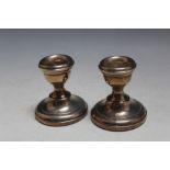 A SMALL PAIR OF HALLMARKED SILVER SQUAT CANDLESTICKS - BIRMINGHAM 1970, having filled bases, H 6 cm