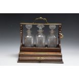 AN OAK THREE BOTTLE TANTALUS WITH DRAW, W 34.75 cm