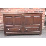 A GEORGIAN OAK OVERSIZED MULE CHEST, the hinged lid above a four panel front and twin drawers below,