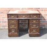 A LATE 19TH CENTURY OAK LEATHER TOPPED TWIN PEDESTAL DESK, the top inset with a red leather