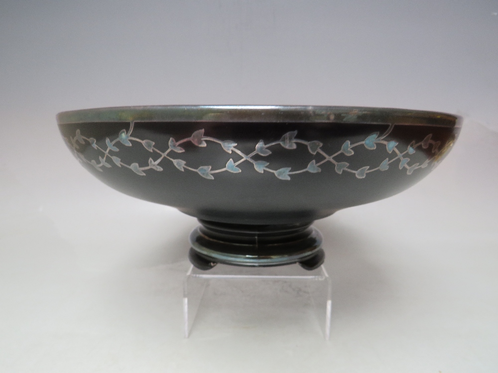 AN EARLY TO MID 20TH CENTURY FOOTED BLACK GLASS BOWL WITH WHITE METAL INLAY, of circular form with