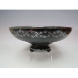 AN EARLY TO MID 20TH CENTURY FOOTED BLACK GLASS BOWL WITH WHITE METAL INLAY, of circular form with