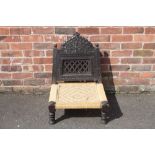 AN UNUSUAL EBONISED TRIBAL LOW STOOL / SEAT, the carved and pierced folding hinged back, above a