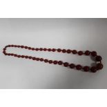 A VINTAGE CHERRY AMBER STYLE GRADUATED BEAD NECKLACE CENTRAL BEAD SIZE 1.7CM