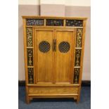 A CHINESE ELM TWO DOOR CABINET, the twin doors with circular pierced panels opening to reveal two