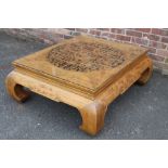 A LARGE CHINESE ELM PIERCED AND CARVED LOW TABLE, supported on four heavy scrolling feet, the top