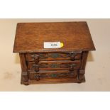 AN OAK JEWELLERY BOX IN THE FORM OF A THREE DRAWER CHEST OF DRAWERS CONTAINING COSTUME JEWELLERY