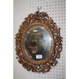 A MODERN BEVEL EDGED WALL MIRROR WITH PIERCED CHERUBIC FRAME, OVERALL H 40 CM, W 32 CM