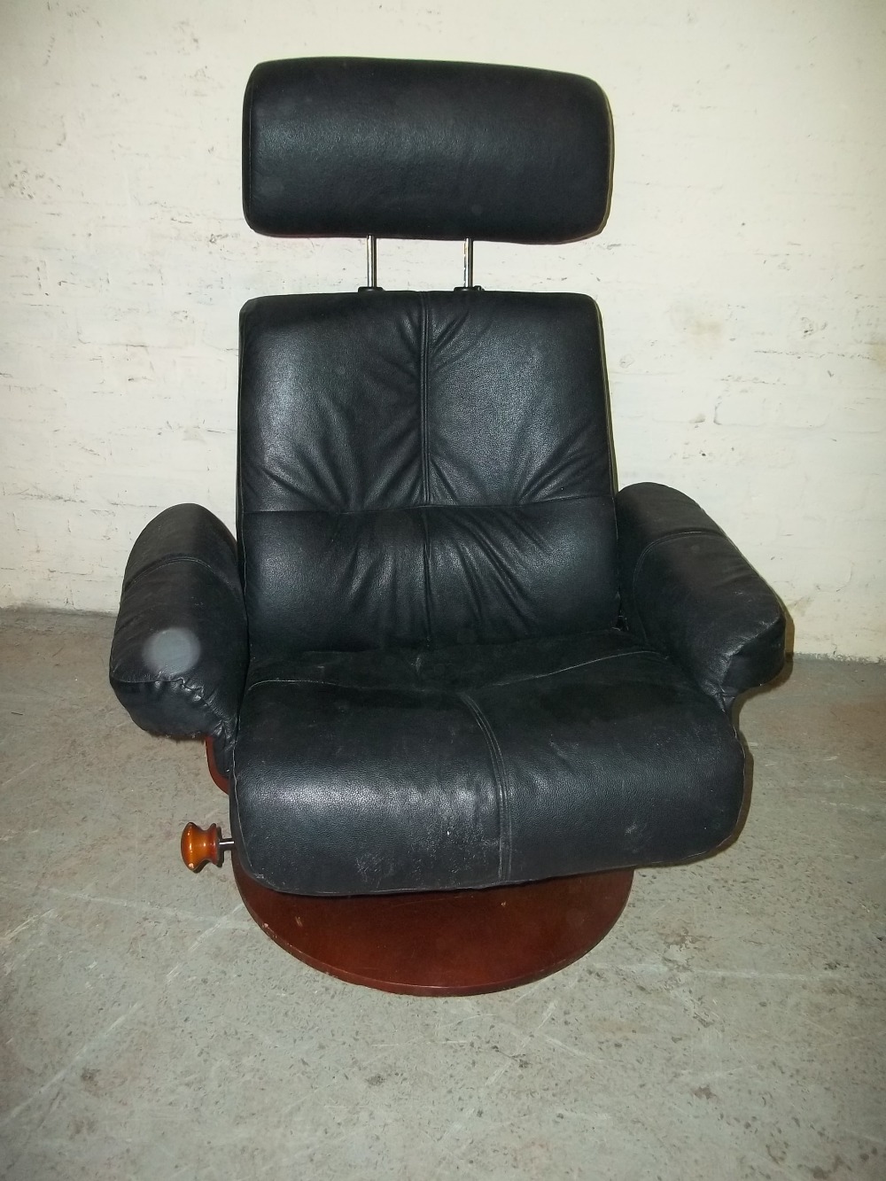 A LARGE BLACK LEATHER SWIVEL RECLINING CHAIR WITH ADJUSTABLE HEADREST