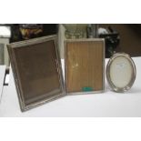 TWO HALLMARKED SILVER PICTURE FRAMES together with a white metal frame, the largest 23 x 17.5 cm