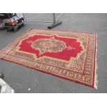 AN EARLY 20TH CENTURY WOOLLEN RUG, MAINLY RED GROUND 197 X 280 CM, A/F, THREADBARE