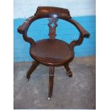 AN ANTIQUE OAK SWIVEL BOWED CHAIR ON BRASS CASTORS, MECHANISM TIGHT