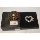 JOAN RIVERS TWO BOXED BROOCHES, A GEM SET CROSS AND A HEART WITH BOW