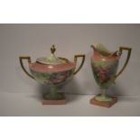 A BELLEEK TWIN HANDLED LIDDED VASE WITH PINK ROSE DECORATION TOGETHER WITH A SIMILAR JUG