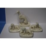 THREE BELLEEK SEATED DOGS TOGETHER WITH ANOTHER ALL WITH GREEN MARKS TO BASE