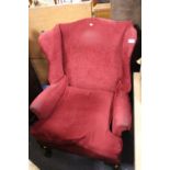 A RED UPHOLSTERED WING BACK ARMCHAIR