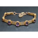 A 9CT GOLD THREE BAR GRADUATING AMETHYST SET GATE BRACELET, set with seven graduating oval