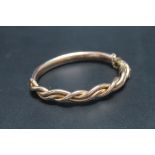 A GOLD AND COPPER BANGLE, having old repair with the three strand intertwined upper section having a