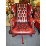 AN OXBLOOD LEATHER OFFICE SWIVEL WINGBACK ARMCHAIR