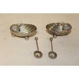 A PAIR OF WHITE METAL SHELL SHAPED SALTS AND SPOONS