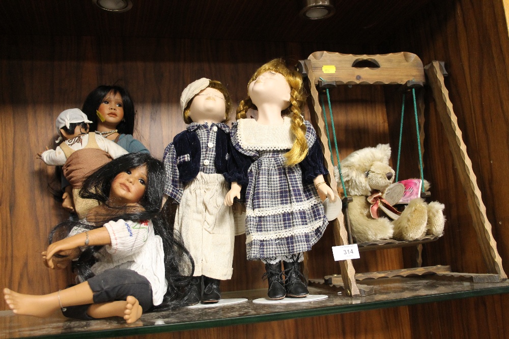 A COLLECTION OF PORCELAIN DOLLS TOGETHER WITH A TEDDY BEAR ON A SWING