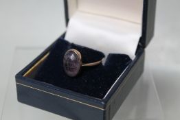 AN ANTIQUE YELLOW METAL AND AMETHYST INTAGLIO RING, carved from the inside of the stone, marked 9c