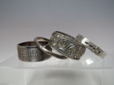 A COLLECTION OF FOUR SILVER AND WHITE METAL BANGLES, to include a sterling silver buckle bangle, a