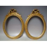 A PAIR OF 20TH CENTURY CARVED WOODEN OVAL DECORATIVE GOLD FRAMES WITH EMBELLISHMENT TO TOP, width of