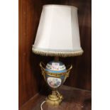 A CONTINENTAL HAND PAINTED TWIN HANDLED CERAMIC AND BRASS TABLE LAMP DECORATED WITH FIGURES AND