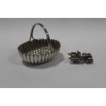 A HALLMARKED SILVER MINIATURE BASKET, TOGETHER WITH A SILVER BRACELET CHARM IN THE FORM OF A VINTAGE