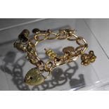 A YELLOW METAL CHARM BRACELET, unmarked bracelet, gold plated clasp, with seven fixed charms and two