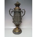 A TALL TWIN HANDED URN SHAPED OIL LAMP, the bronzed metal body with fine embossed detail