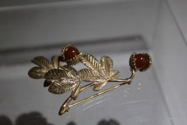 A HALLMARKED 9CT LEAF BROOCH, designed as three Horse Chestnut tree leaves adorned with two conkers,