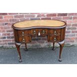 AN EARLY TWENTIETH CENTURY MAHOGANY AND LEATHER TOPPED KIDNEY SHAPED DESK, with five drawers, raised