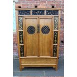 A CHINESE ELM TWO DOOR CABINET, the twin doors with circular pierced panels opening to reveal two