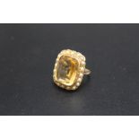 A VINTAGE DRESS RING, set with a large citrine style stone surrounded by seed peals, in unmarked