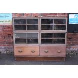 A LARGE VINTAGE OAK GLAZED HABERDASHERY STYLE CABINET, in two sections, the bottom section with