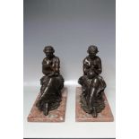 A PAIR OF BRONZE SEATED MAIDENS SIGNED TO THE BASE 'COUVAN'; one with a book, the other with a