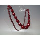 A VINTAGE SINGLE STRAND CHERRY AMBER GRADUATED BEAD NECKLACE, central bead approx Dia. 2 cm,
