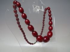 A VINTAGE SINGLE STRAND CHERRY AMBER GRADUATED BEAD NECKLACE, central bead approx Dia. 2 cm,