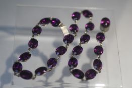 A VINTAGE HAND CRAFTED WHITE METAL AND AMETHYST TYPE COLLARETTE, set with 24 oval faceted stones,